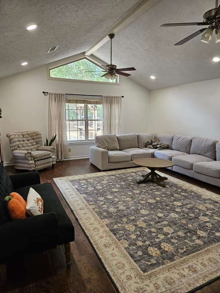 Living room with a gray sectional, patterned rug, vaulted ceiling, and window.