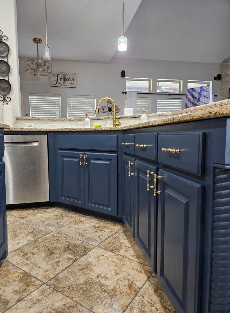 Blue kitchen cabinets with gold hardware, stainless steel appliances, and a gold faucet.
