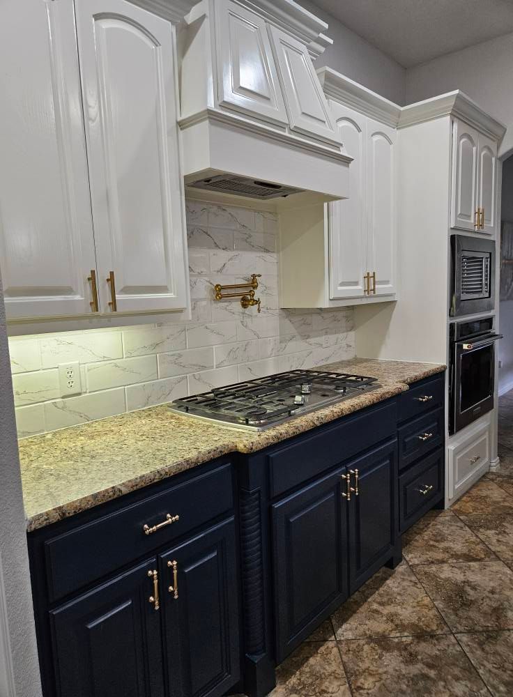 Kitchen with navy blue lower cabinets, white upper cabinets, granite countertop, and stainless steel appliances.