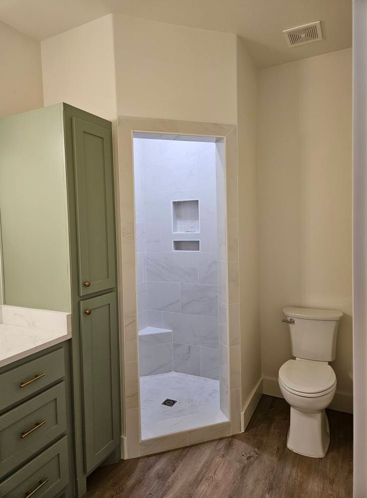 Bathroom interior with green cabinets, white shower, and toilet.