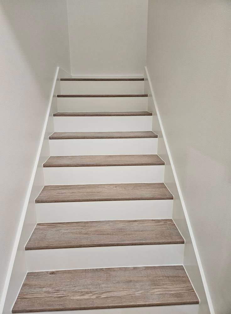 Staircase with light gray walls, white risers, and wood-look treads. View looking up.