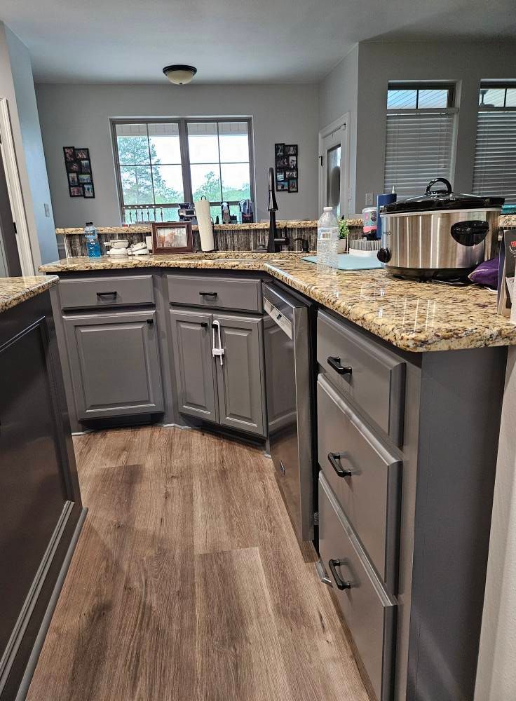 Kitchen with gray cabinets, wood floors, and granite countertops. A slow cooker sits on the counter.