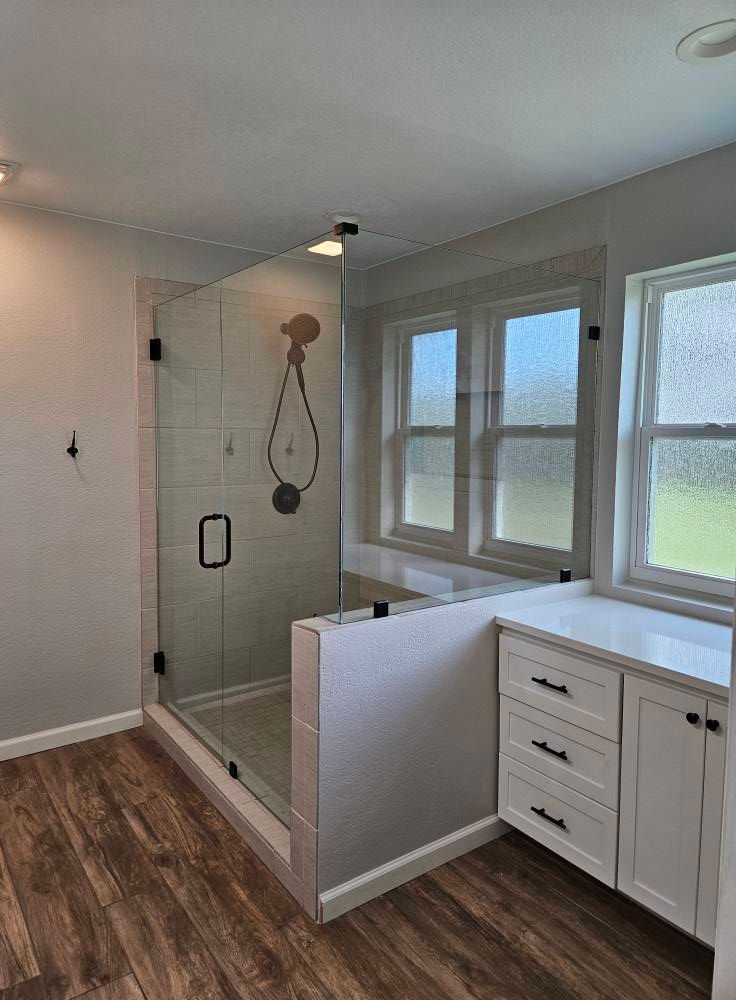 Modern bathroom with glass shower, white vanity, and window.