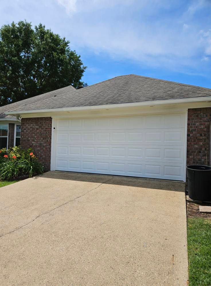 White garage door on a brick home with concrete driveway under a blue sky.