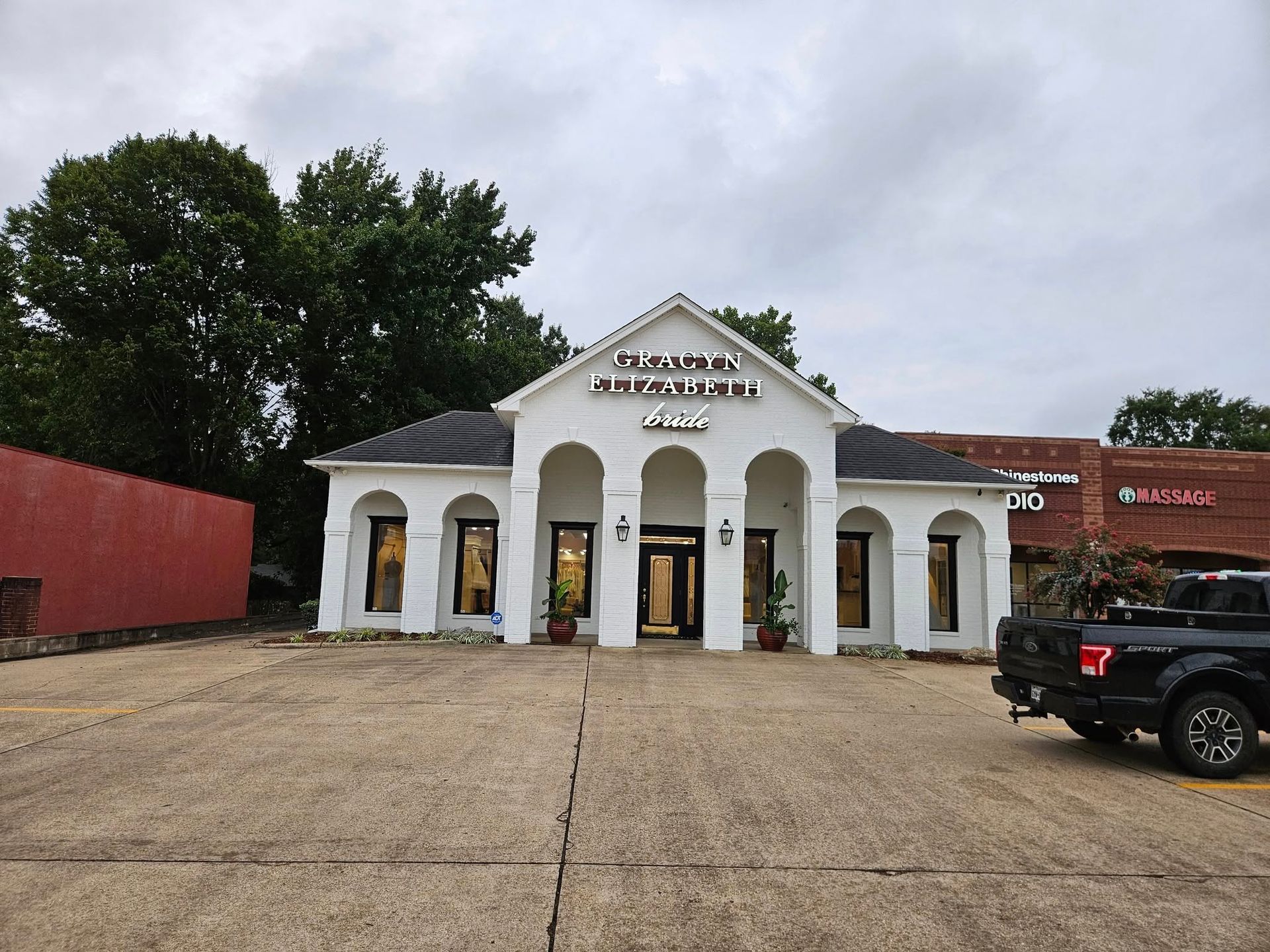 White building with arched windows and door; sign says 