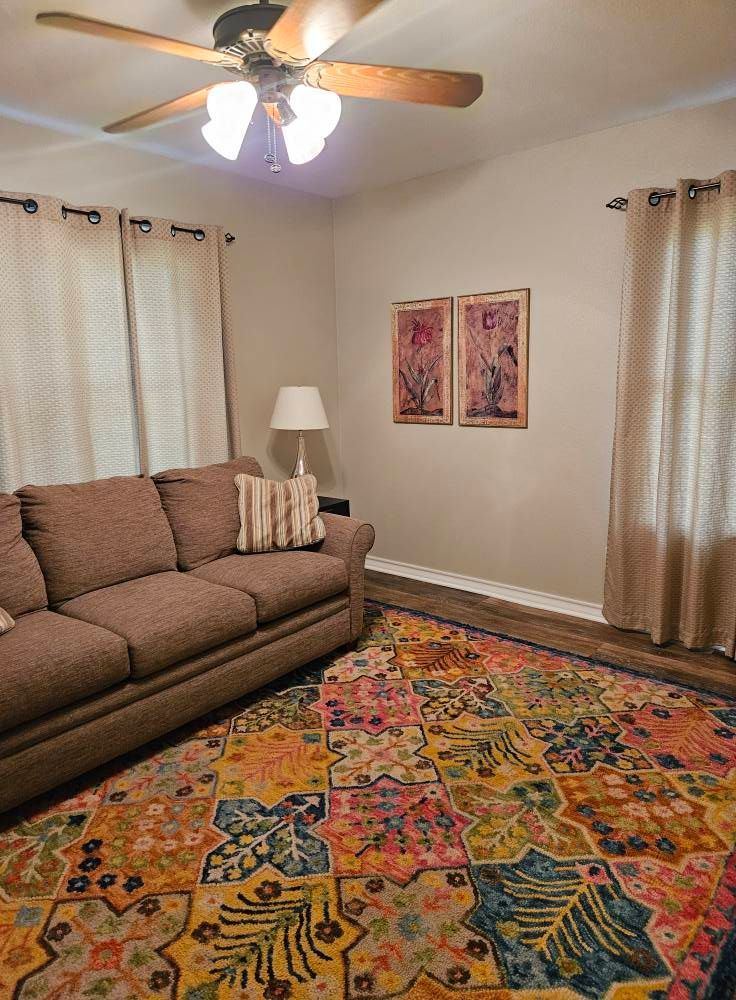 Living room with brown sofa, colorful rug, beige walls, and artwork.