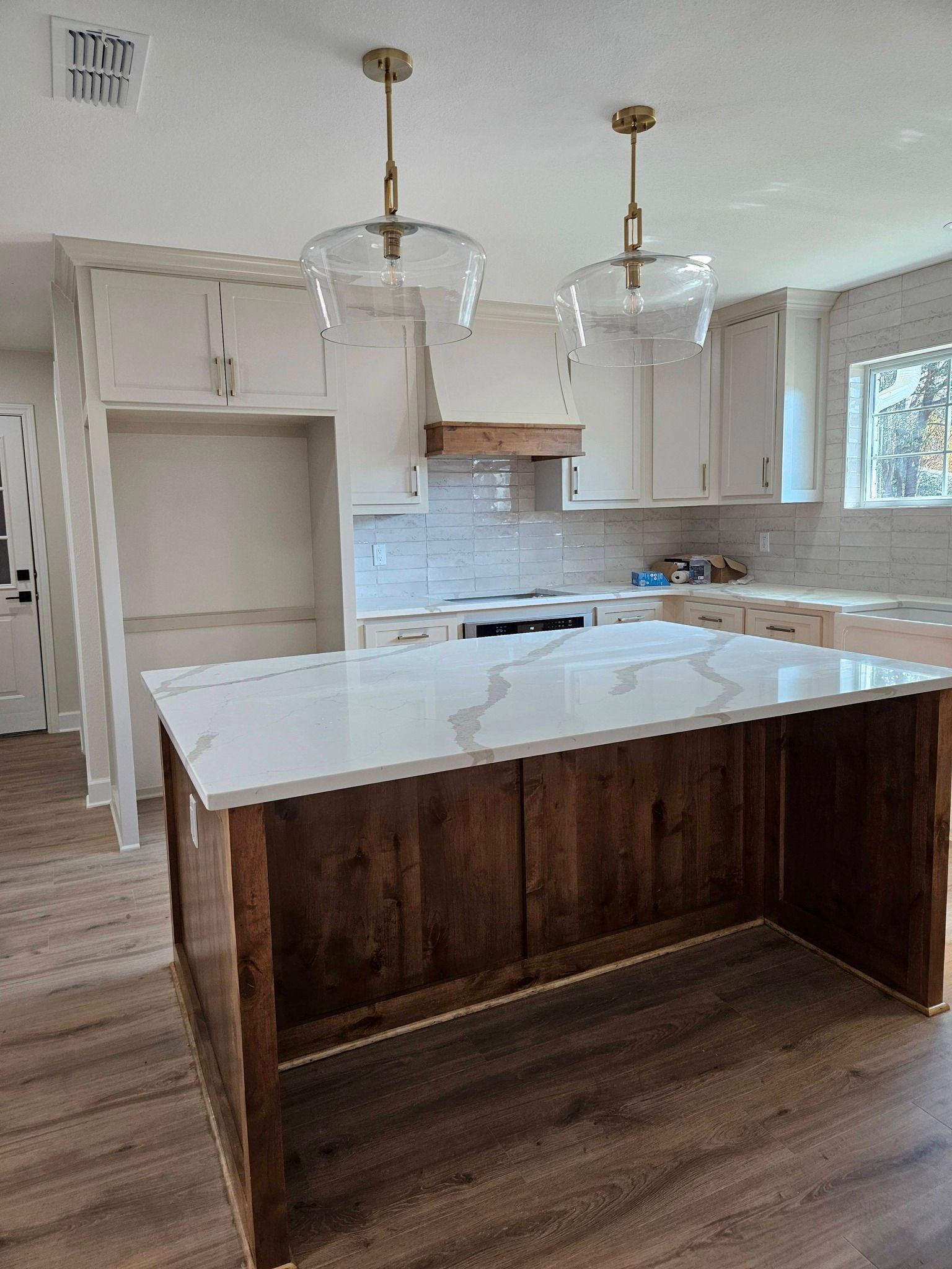 Kitchen with white cabinets, dark wood island, and two pendant lights.