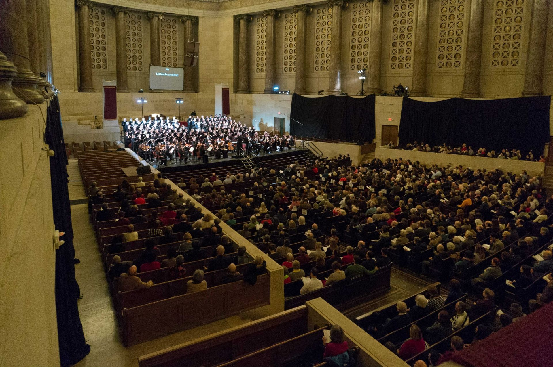 A large auditorium filled with people watching an orchestra perform