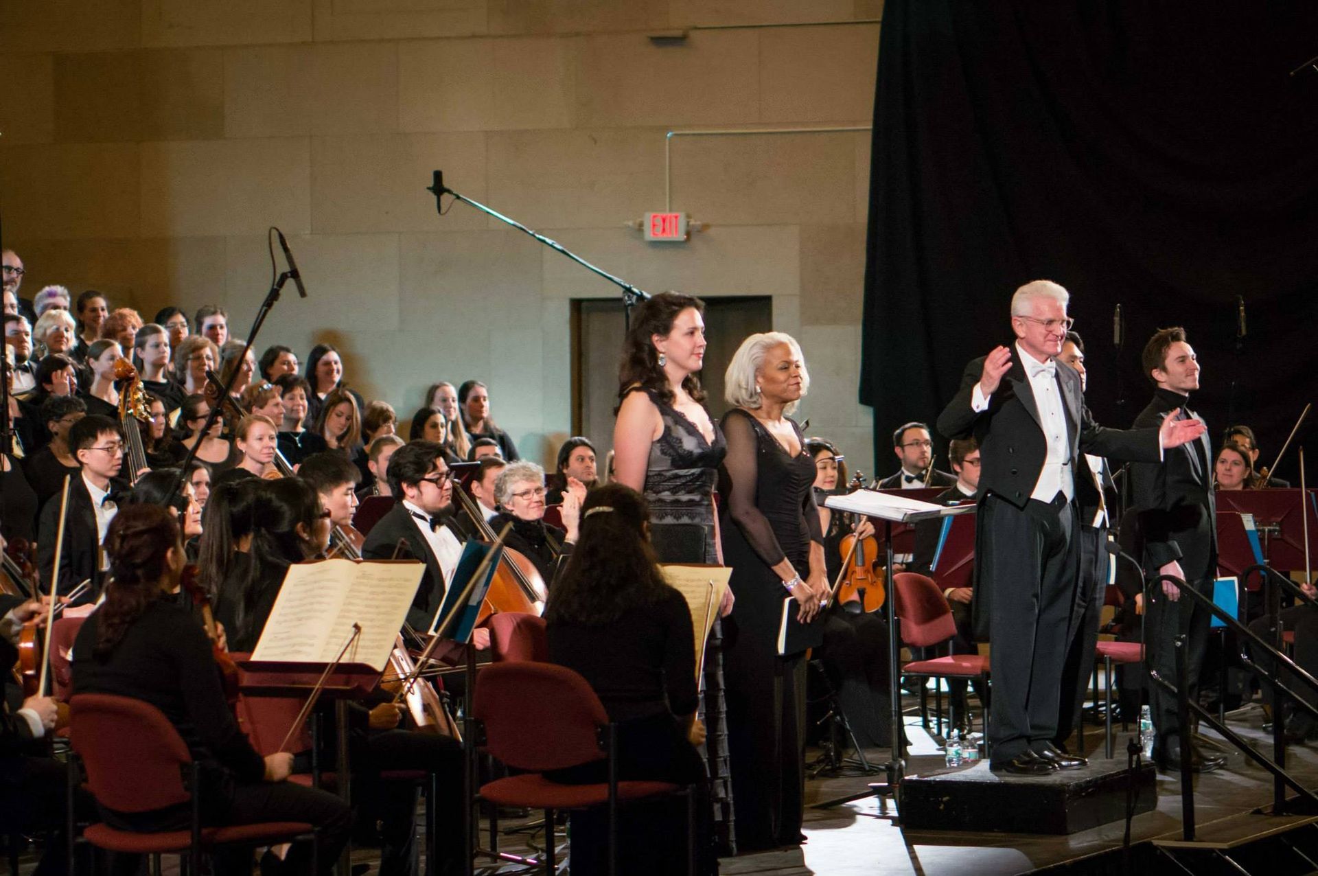 A group of people are standing in front of an orchestra on a stage.