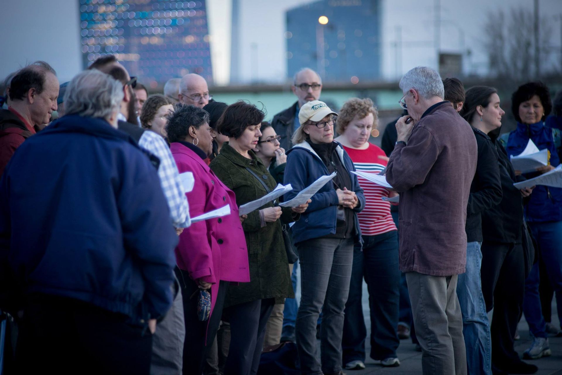 A group of people are singing in a choir outside.