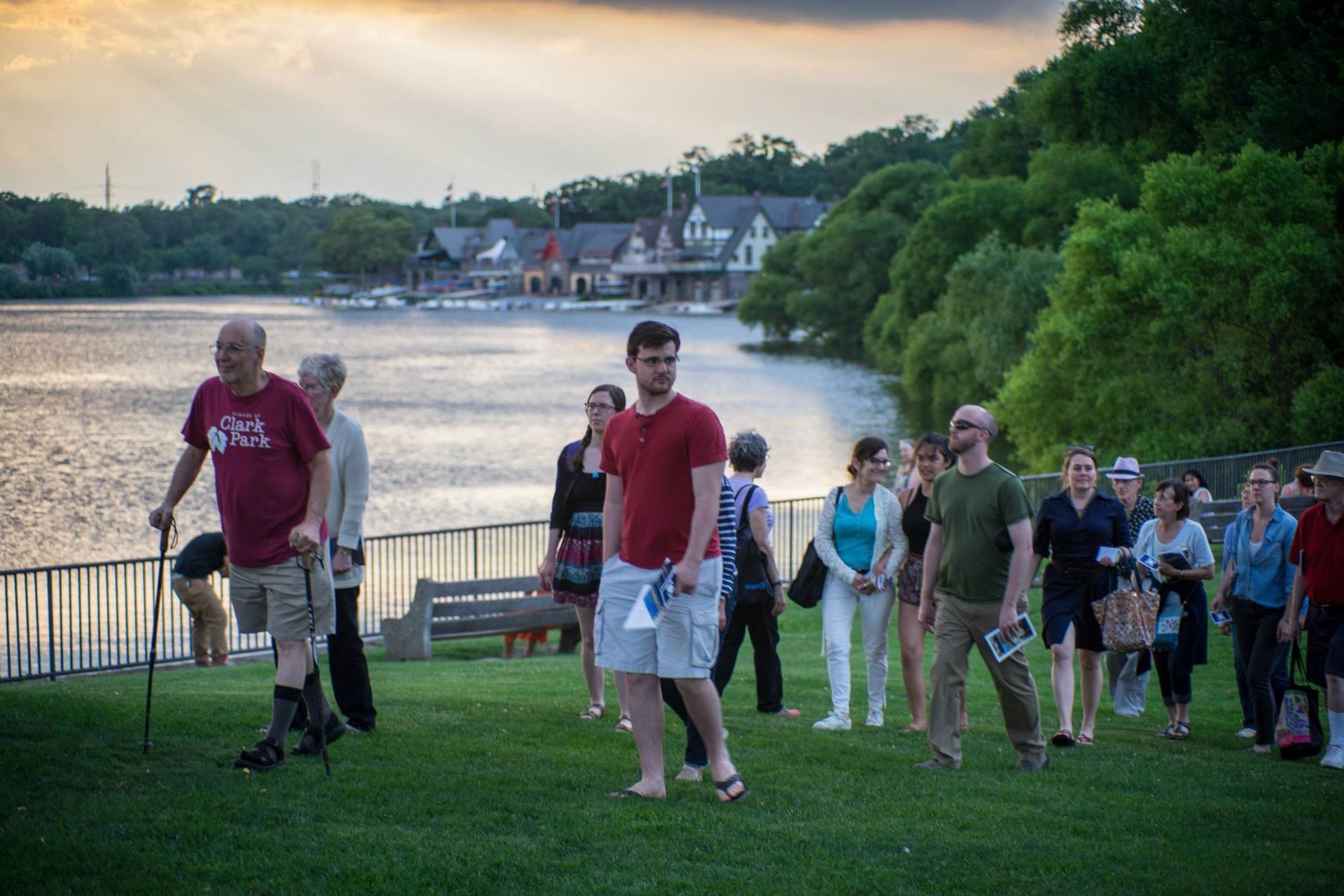 A group of people are standing on top of a lush green field next to a body of water.