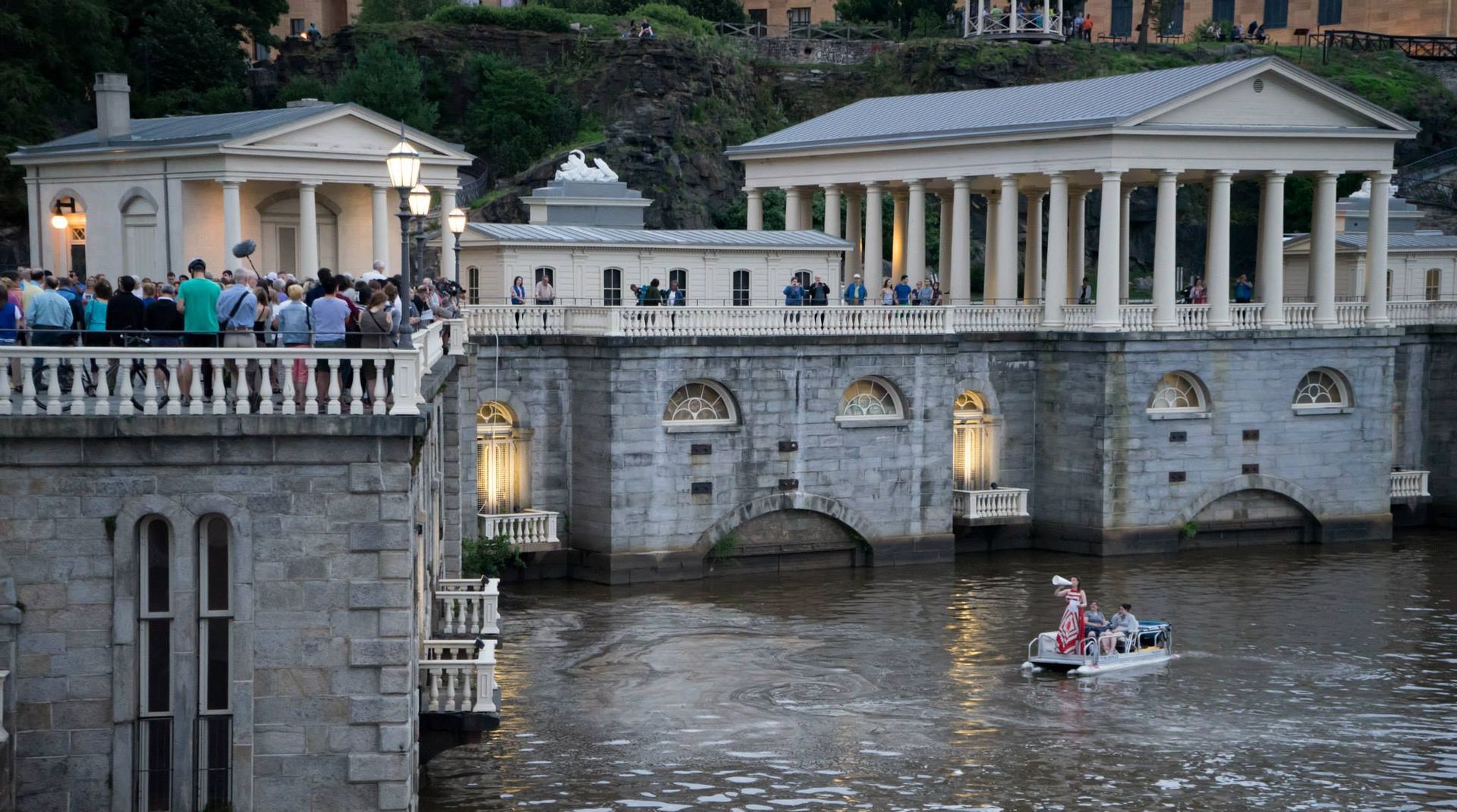 A group of people are sitting on a balcony overlooking a river.