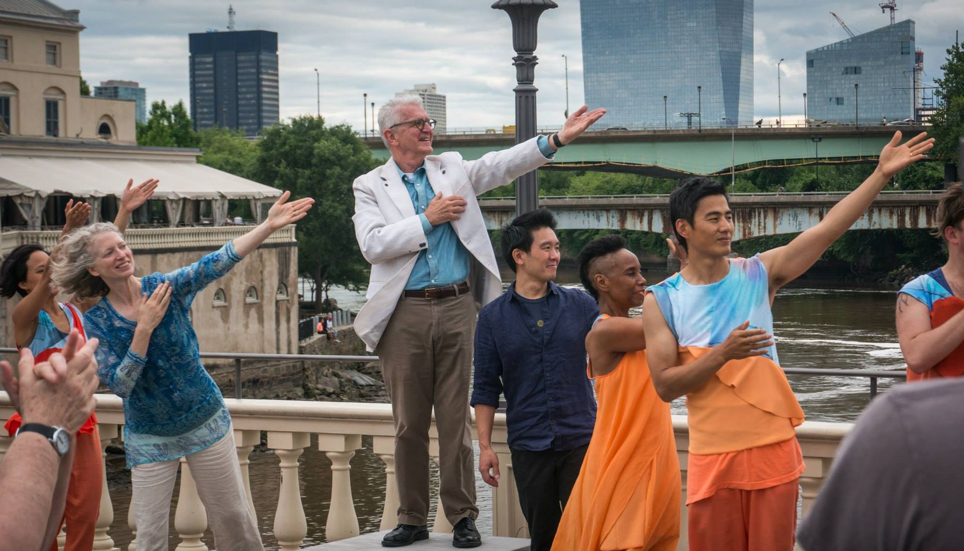 A group of people are standing on a bridge with their arms outstretched.