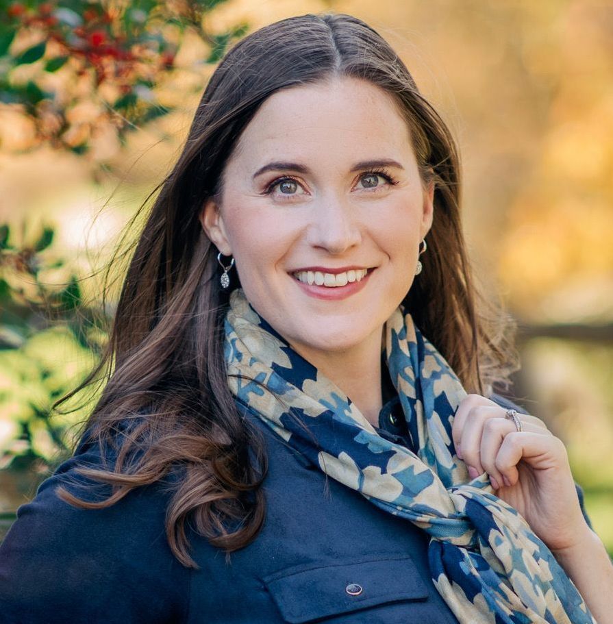 A woman wearing a scarf and earrings is smiling for the camera.
