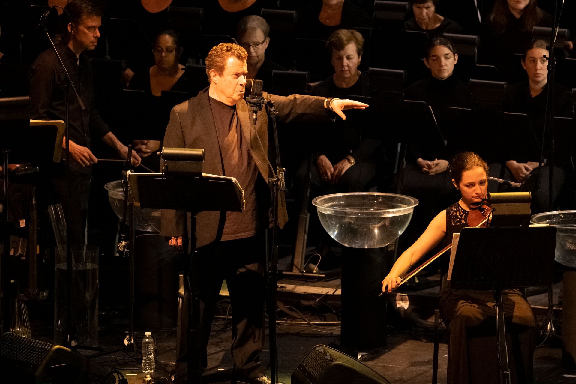 A woman playing a violin in front of an orchestra