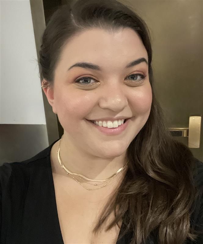 A woman in a blue shirt is smiling for the camera