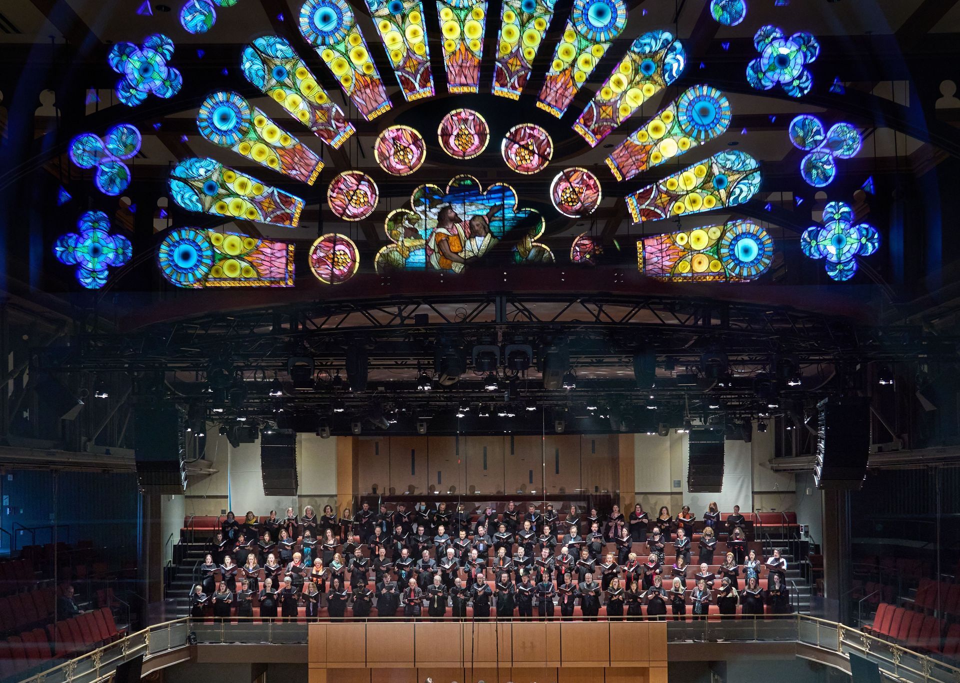 A large stained glass window hangs above a large choir