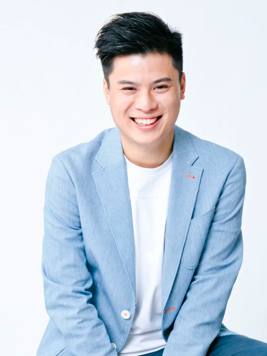 Smiling person in a light blue blazer and white shirt against a white background