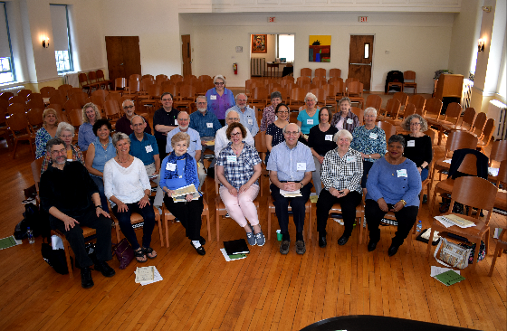 A large group of people are sitting in chairs in a room.