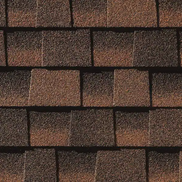 A close-up view of overlapping asphalt roofing shingles in various shades of brown and charcoal.