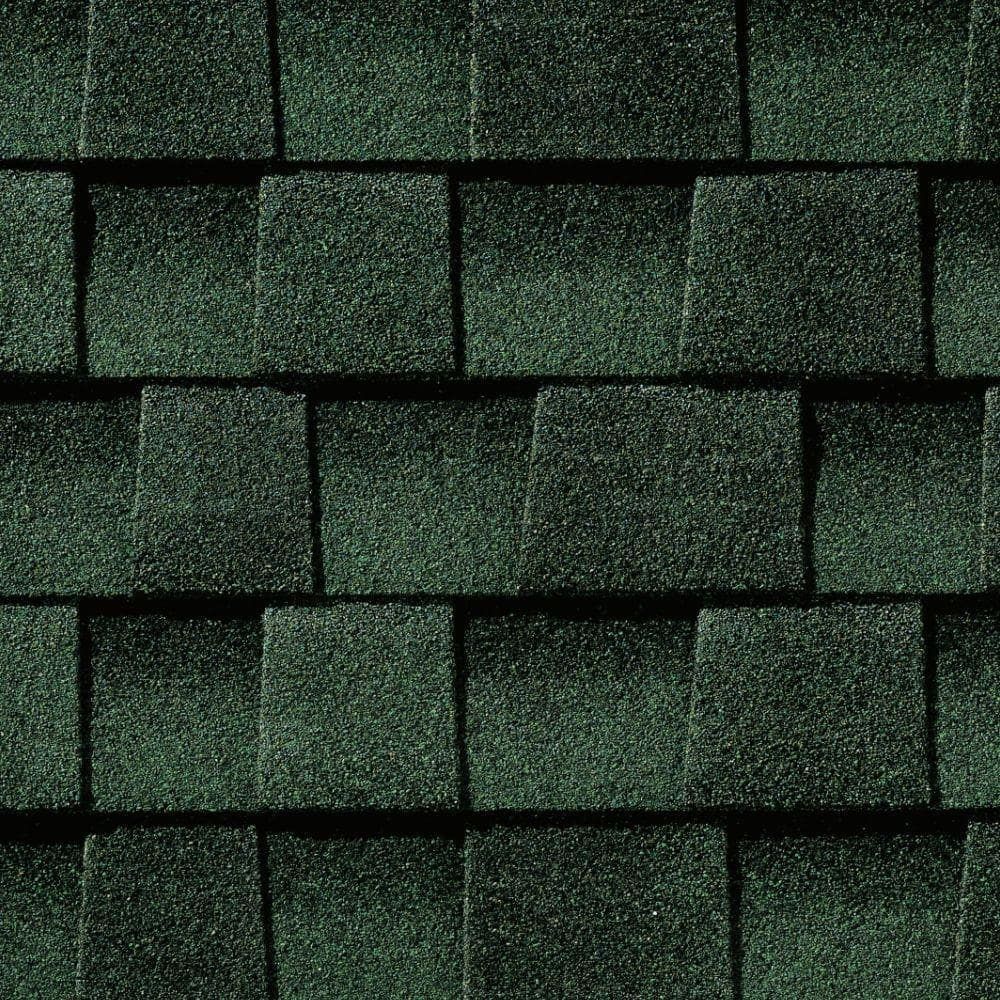 Close-up of overlapping dark green architectural asphalt roof shingles with a textured, layered appearance.