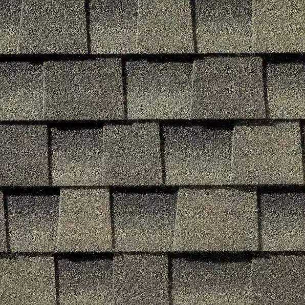 Close-up view of overlapping grey-brown asphalt roofing shingles with a textured, layered pattern.