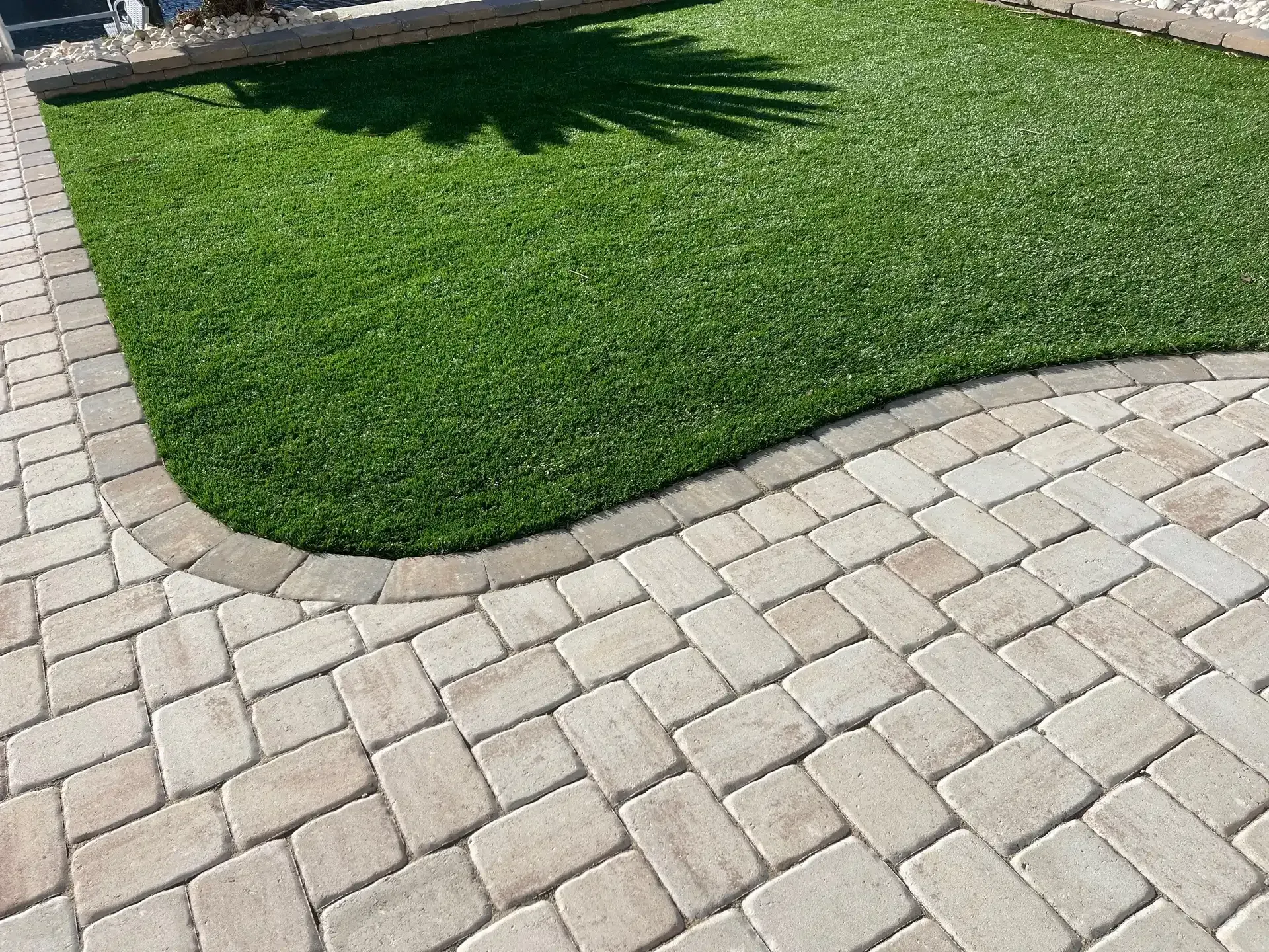Curved stone pavers border a green lawn in a landscaped yard.