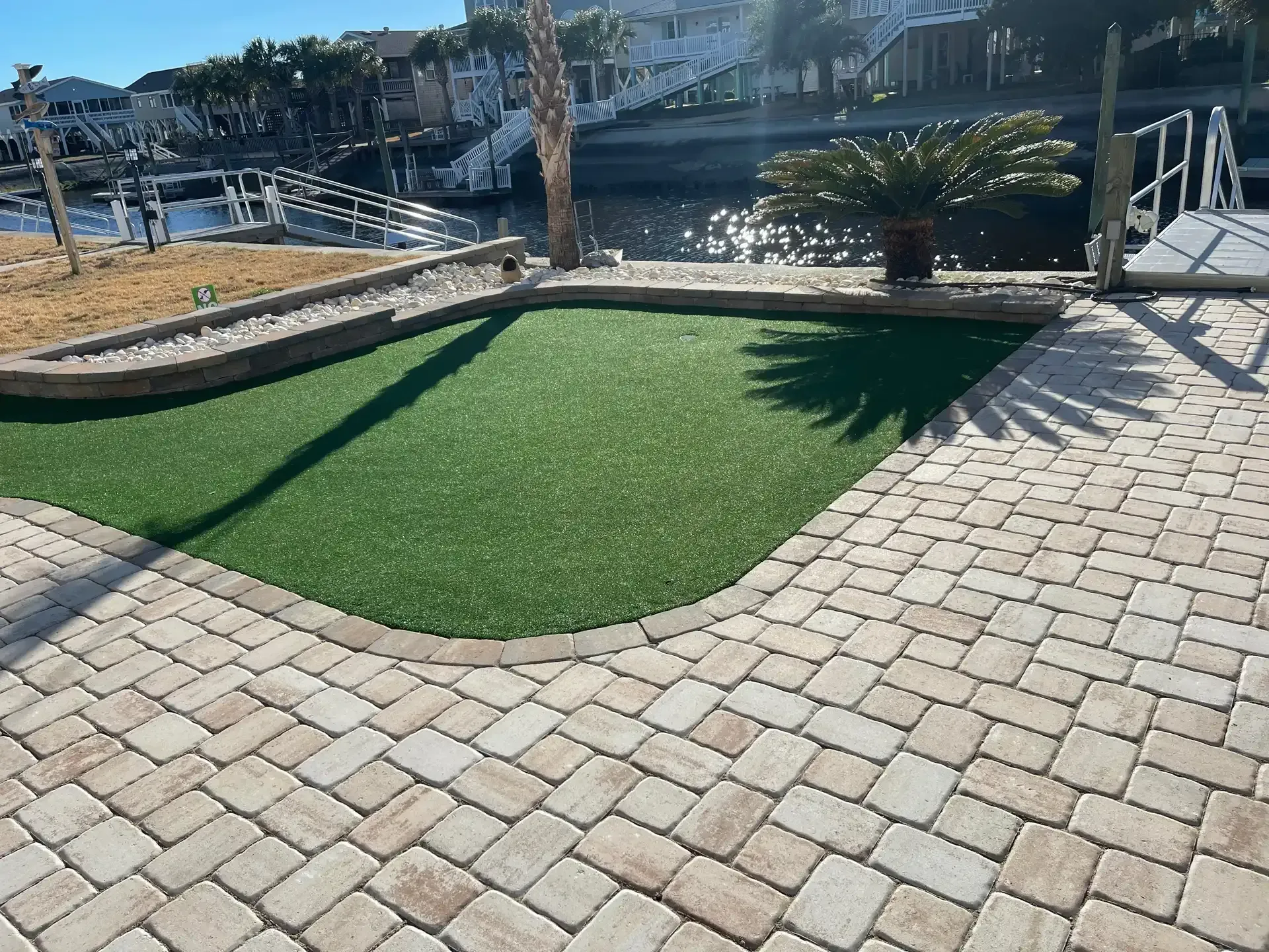 Courtyard patio with pavers, artificial turf, and a canal view in bright sunlight