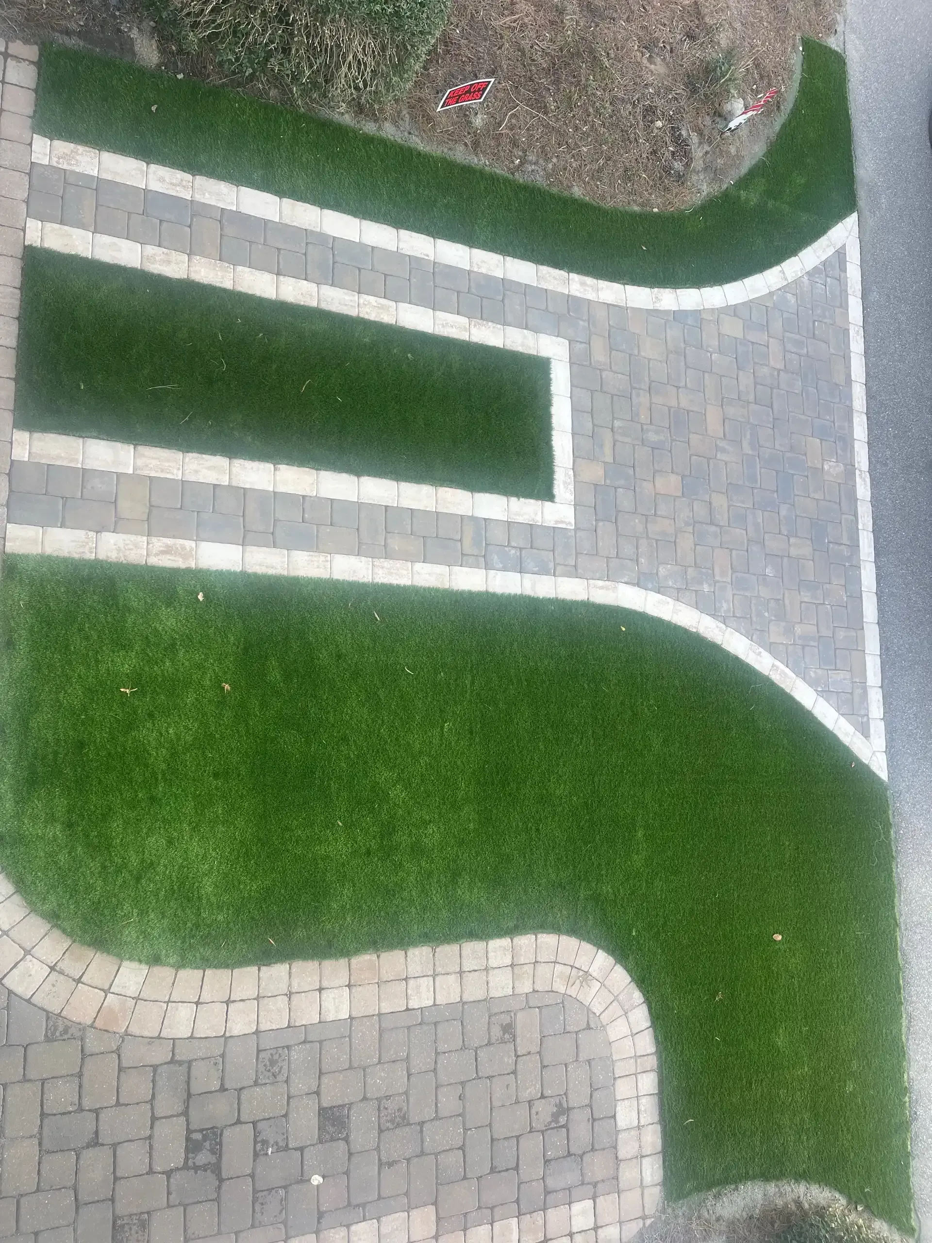 Aerial view of a landscaped garden with green grass and curved gray stone paths