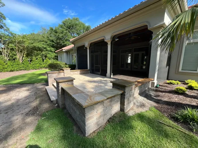 Stone patio steps leading to a covered porch on a sunny suburban home with landscaped yard