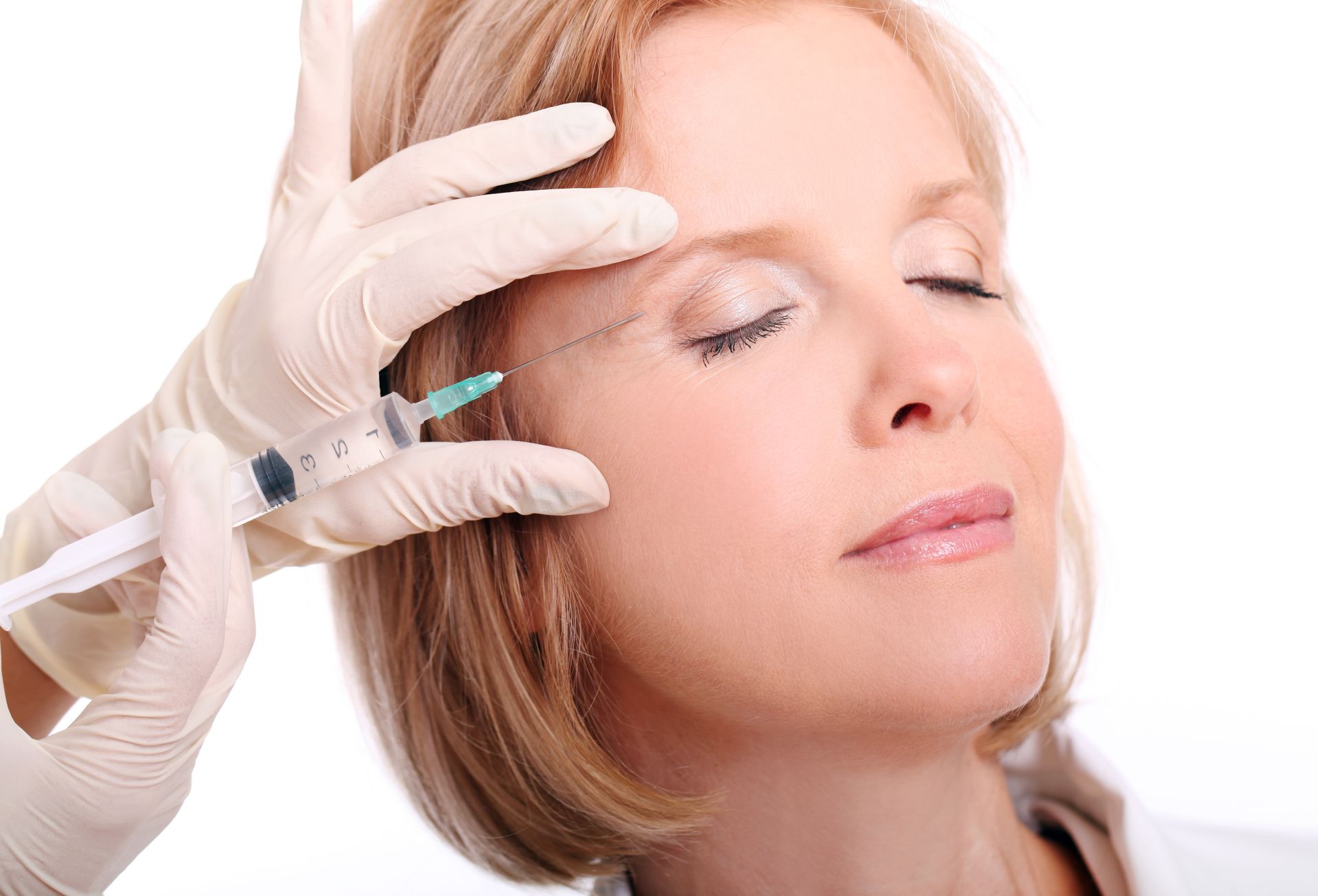 Gloved hand administering facial injection to a reclining person with eyes closed