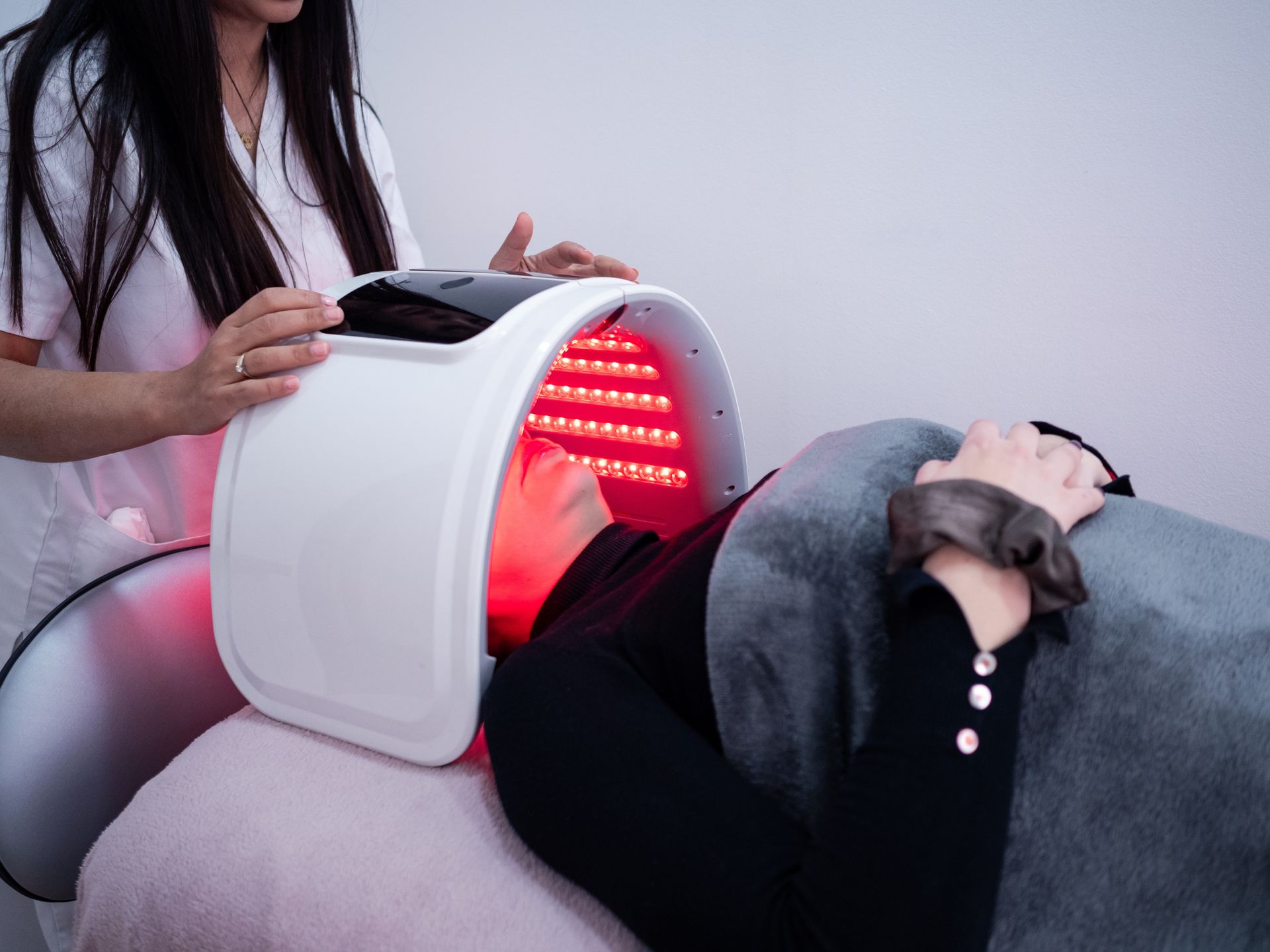 A woman is getting a red light treatment on her face.