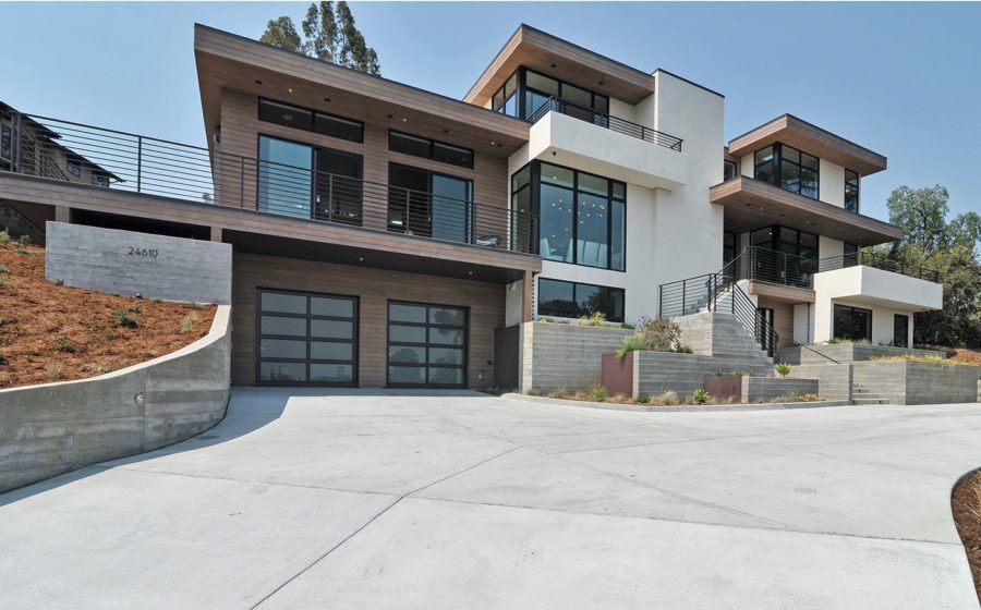 Modern luxury house with large windows, brown-and-white exterior, and a wide concrete driveway