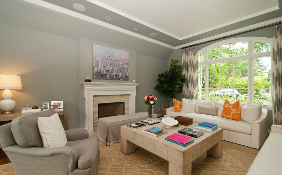 Bright living room with fireplace, beige seating, coffee table, and large arched window