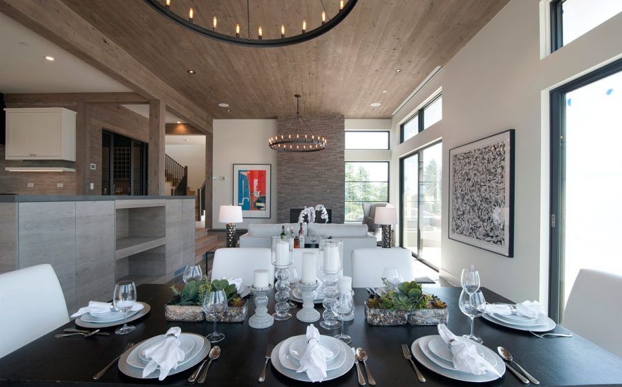 Modern dining room with a set table, high ceiling, and large windows overlooking the outdoors