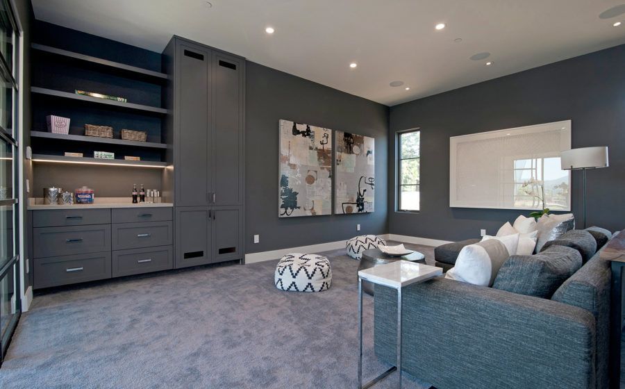 Modern living room with gray walls, built-in shelves, sectional sofa, and abstract wall art