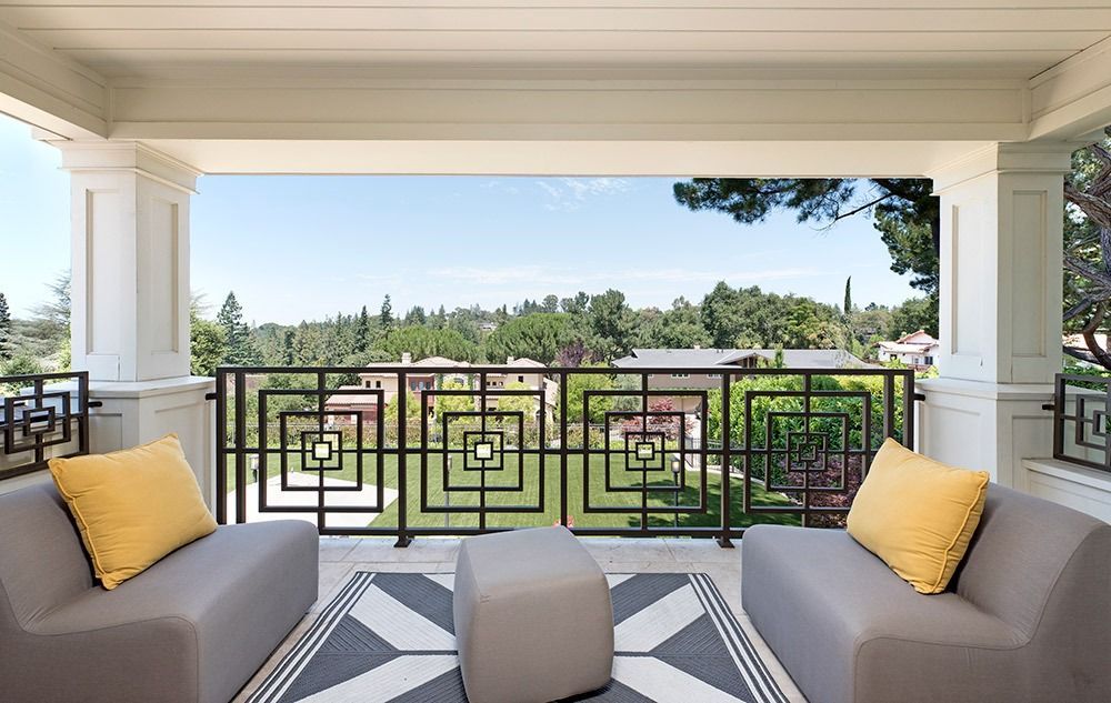 Covered patio seating with gray sofas, yellow pillows, and a view of a landscaped golf course