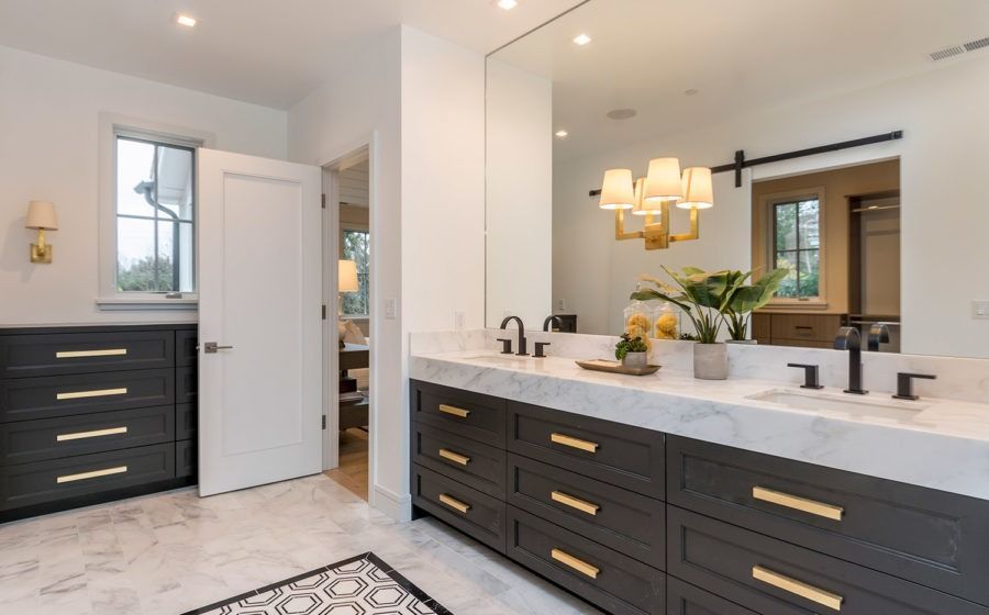 Modern bathroom with double vanity, marble counters, black cabinets, and a large mirror.