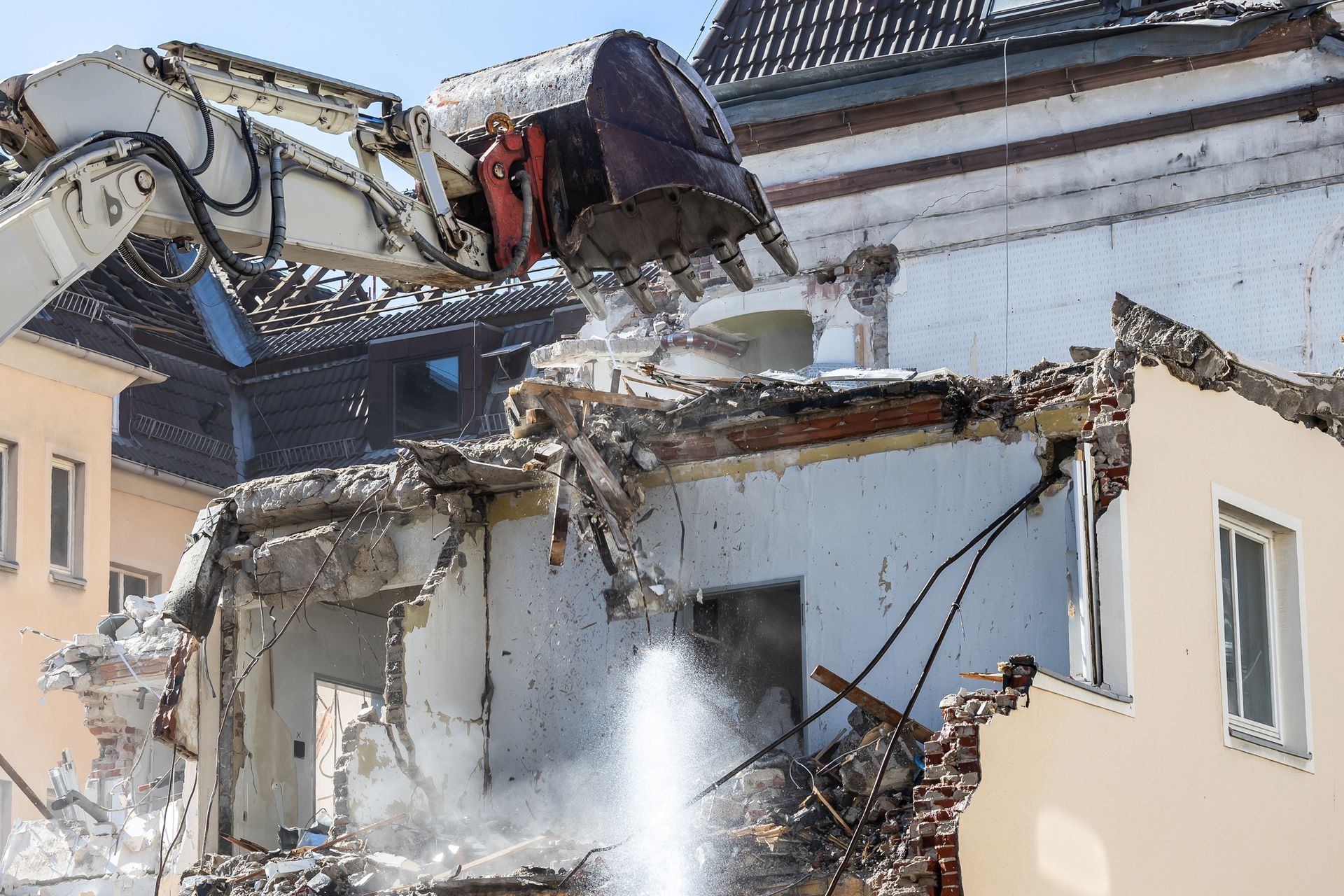 House demolition in progress with heavy machinery tearing down structure.