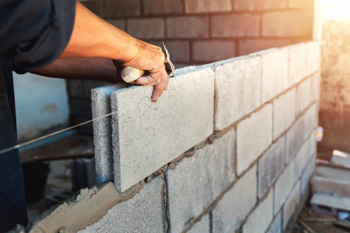 Worker laying concrete blocks on a wall at a construction site