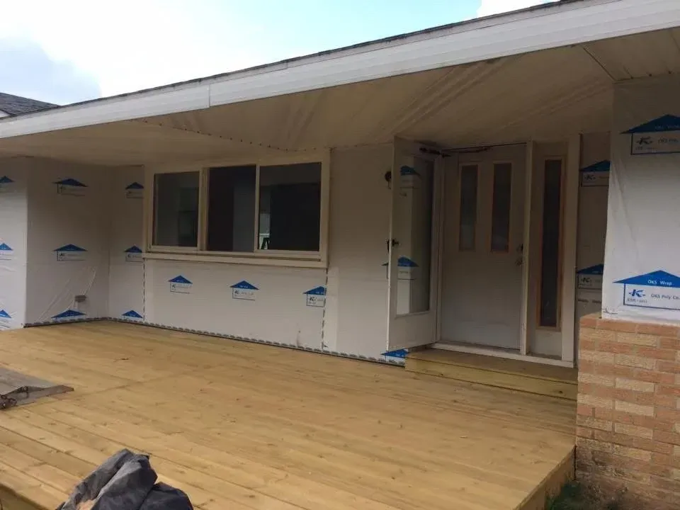Partially built house porch with wood decking, windows, and exterior siding under construction