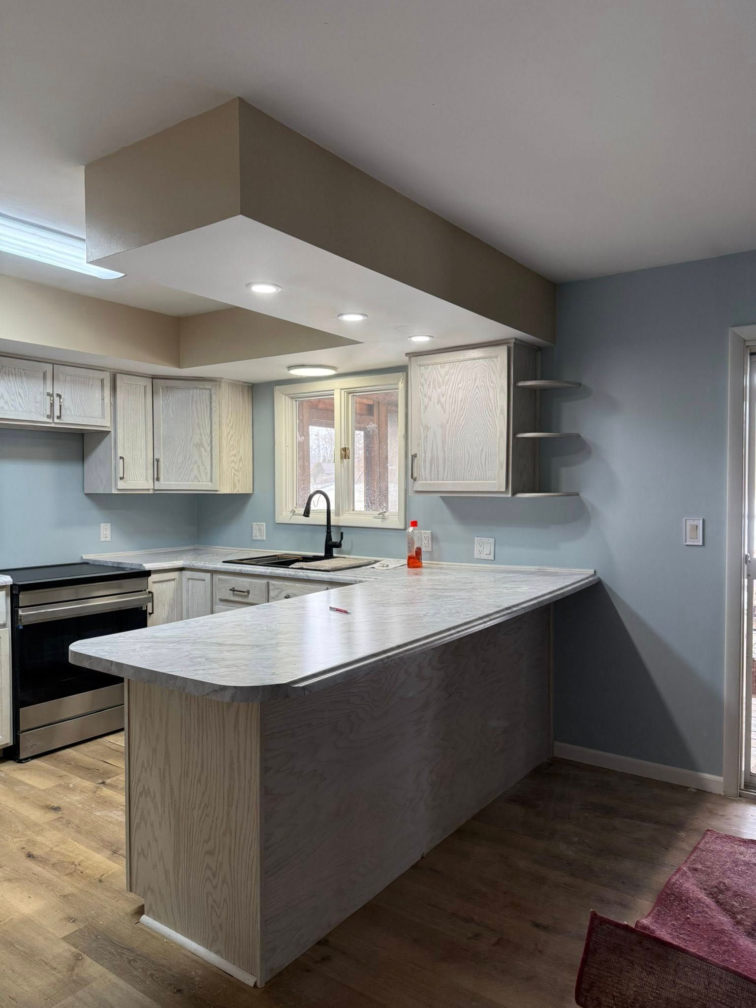 Modern kitchen with white island, beige cabinets, dark wood floor, and recessed ceiling lights