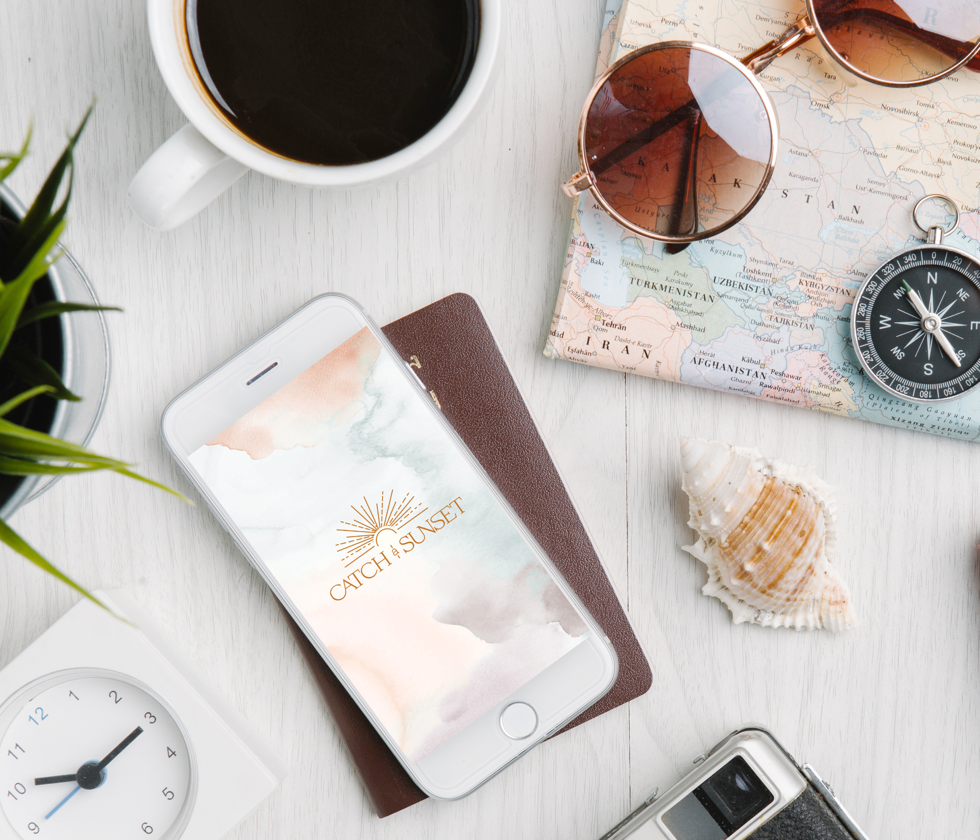 A cell phone is sitting on a table next to a cup of coffee and a compass.