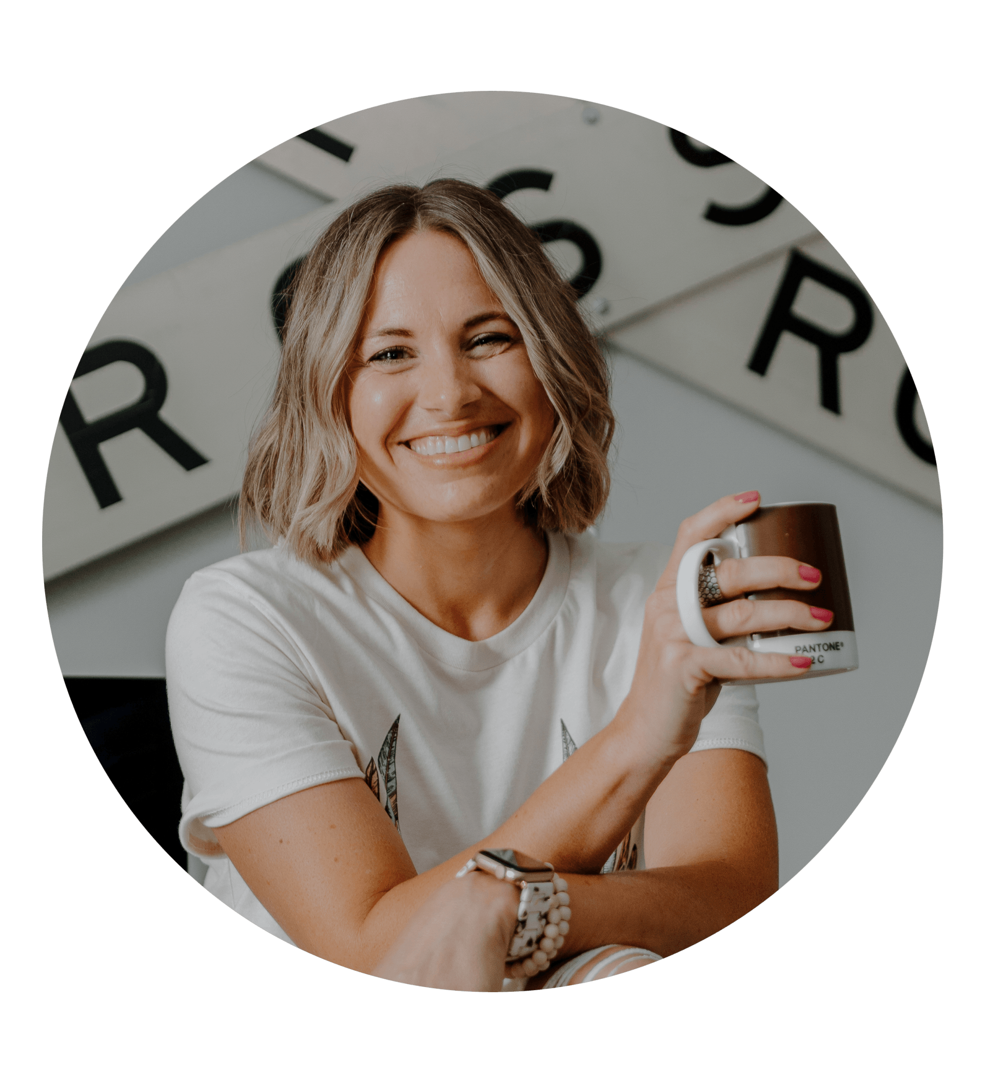 A woman in a white shirt is smiling while holding a cup of coffee