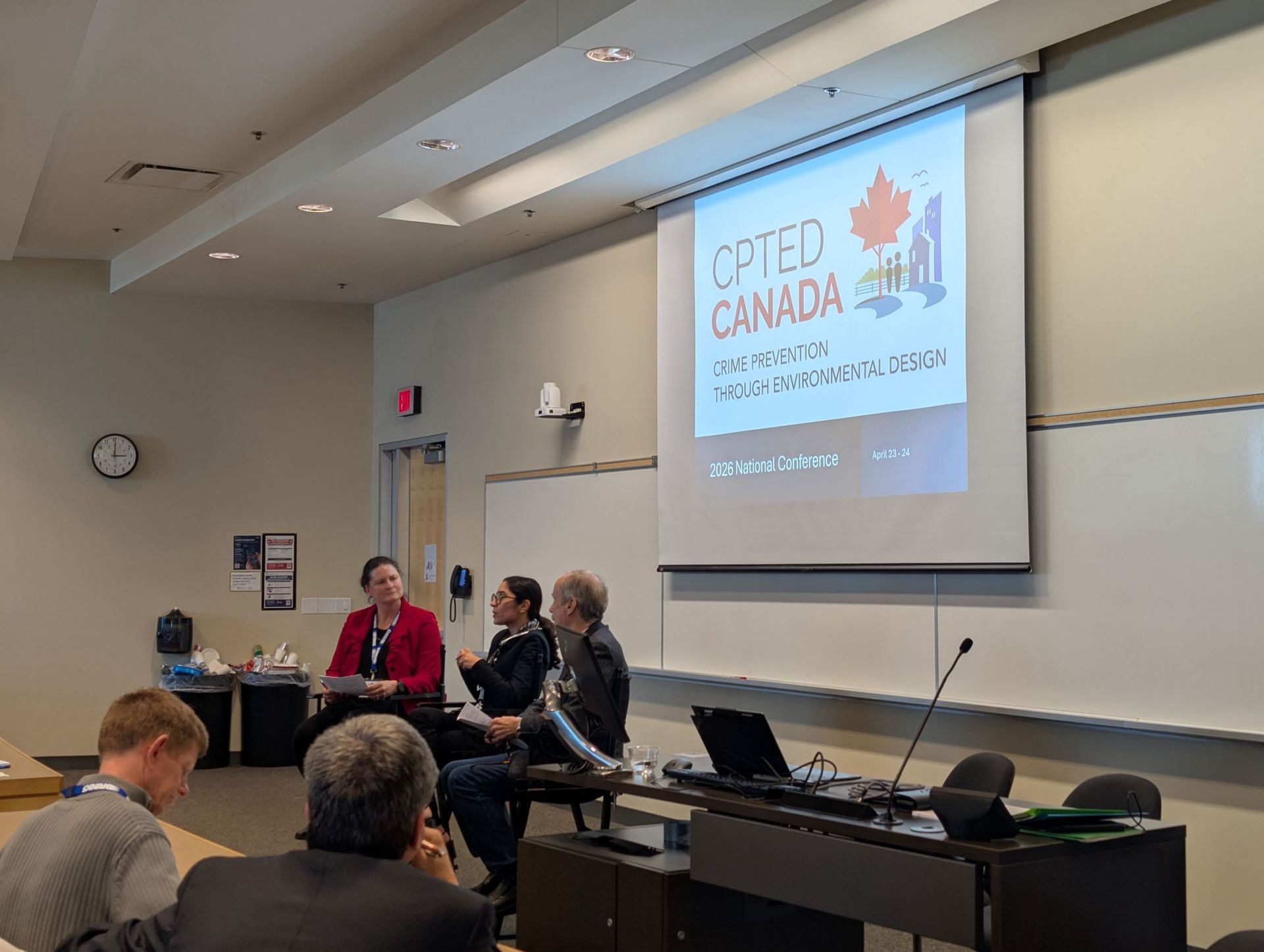 Conference panel in lecture hall with three speakers beneath a projected “COPED Canada” slide.