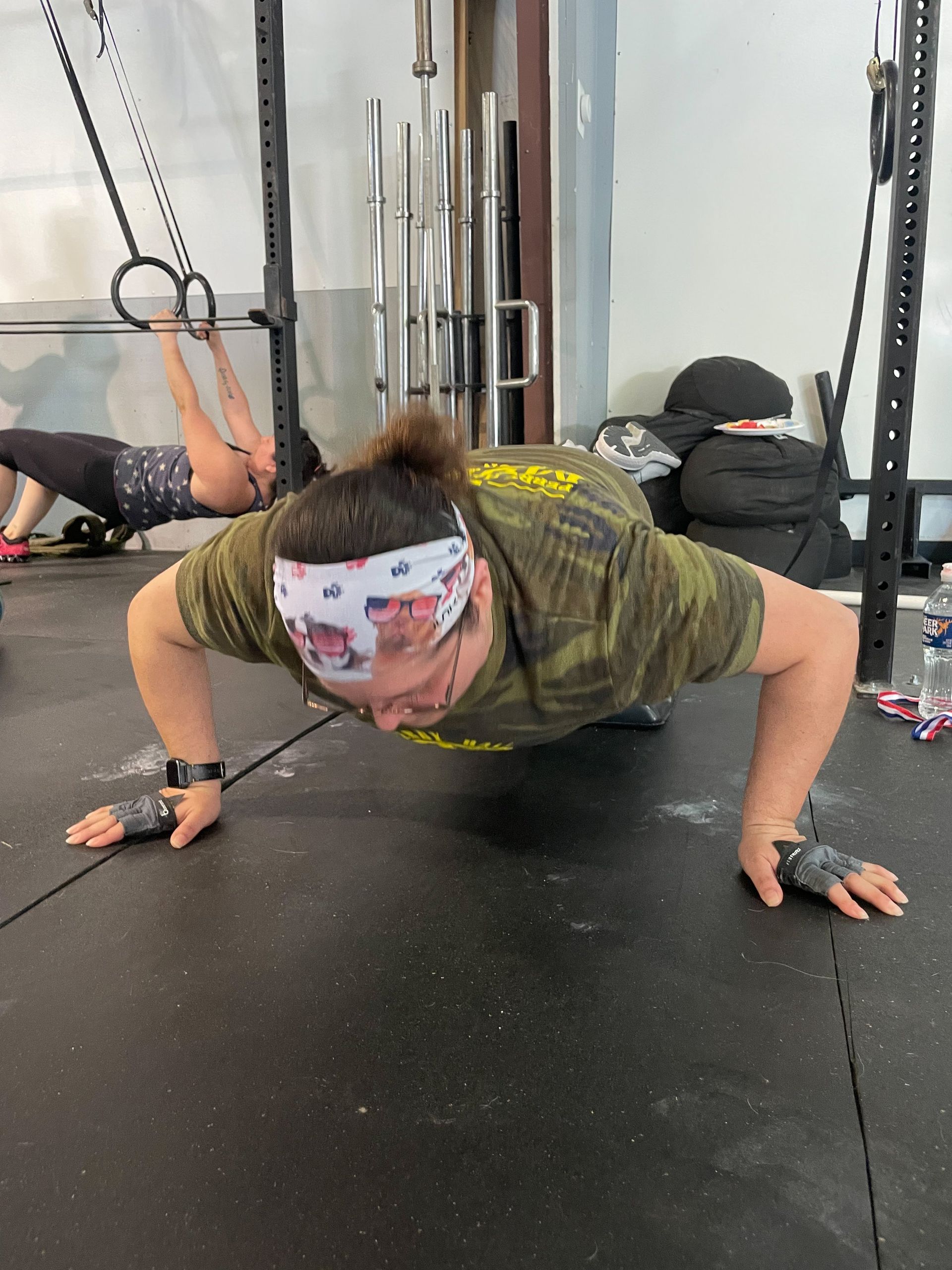 Person doing a push-up on a gym floor, wearing a camouflage shirt and patterned headband.at Perry Hall Fitness & Performance in White Marsh, MD
