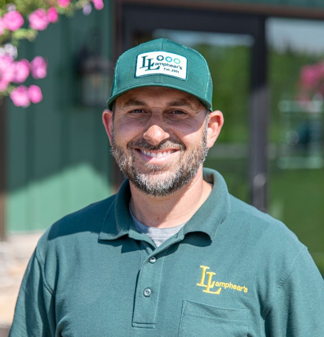 Man in green hat and shirt smiling outdoors.
