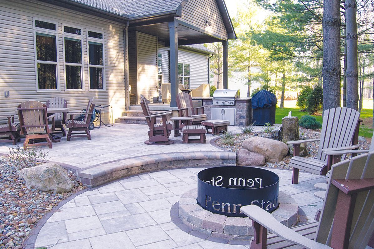 Backyard patio with fire pit, grill, and Adirondack chairs.