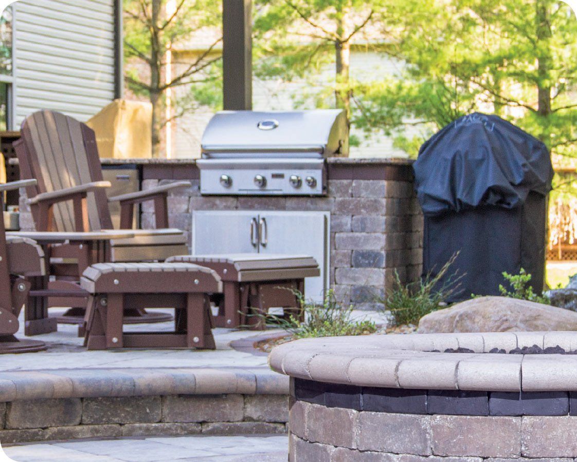 Outdoor kitchen with grill, seating, and fire pit.