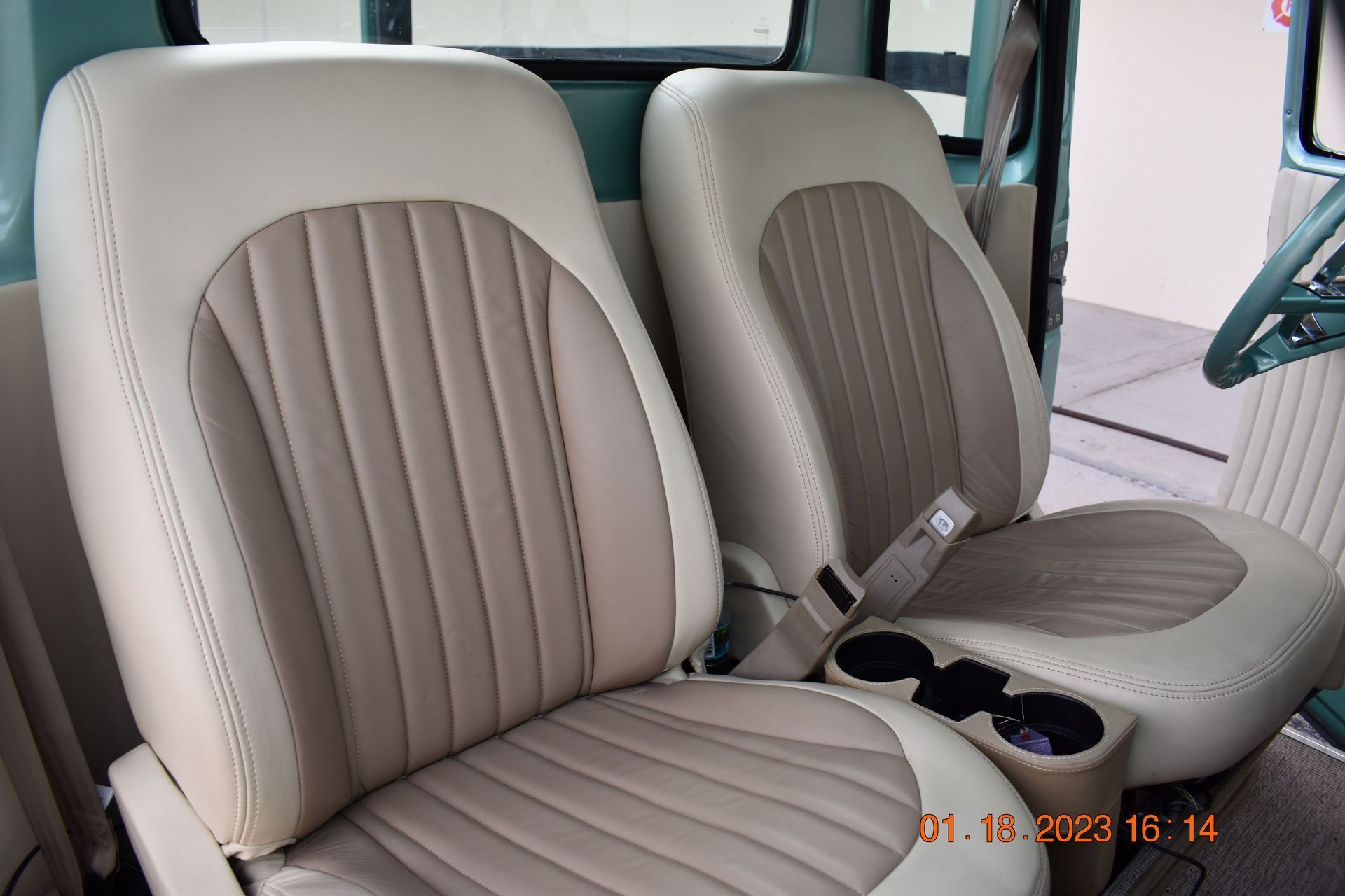 Tan and beige car seats with vertical stitching inside a vehicle interior.